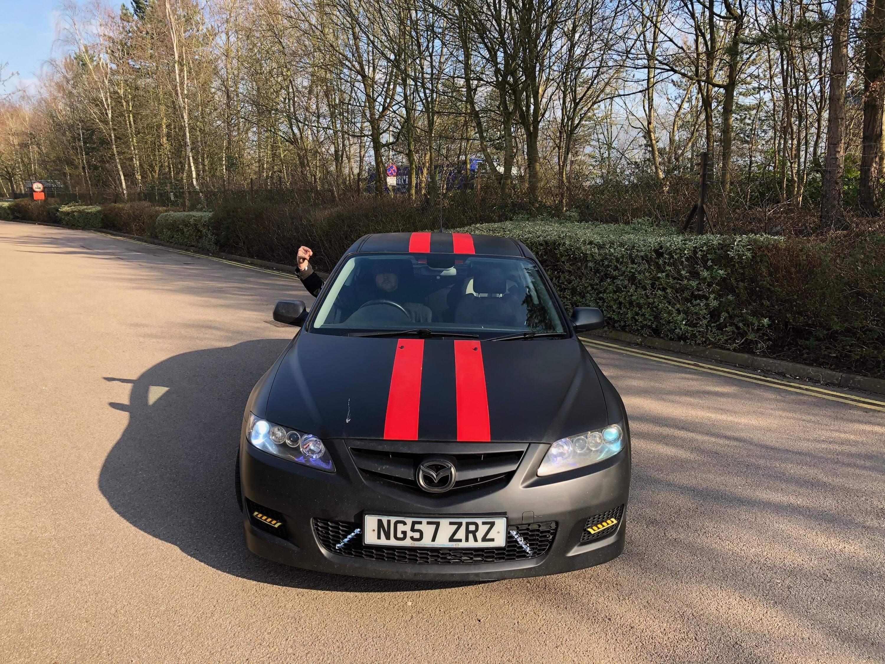 A black Mazda with red racing stripes, facing the camera