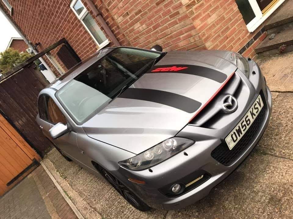 A silver Mazda with black bonnet graphics